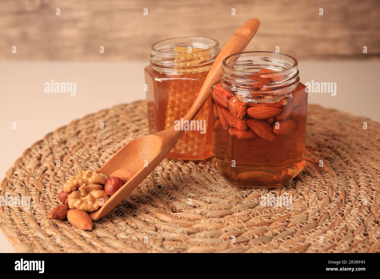 Jars with honey and different nuts on beige table Stock Photo