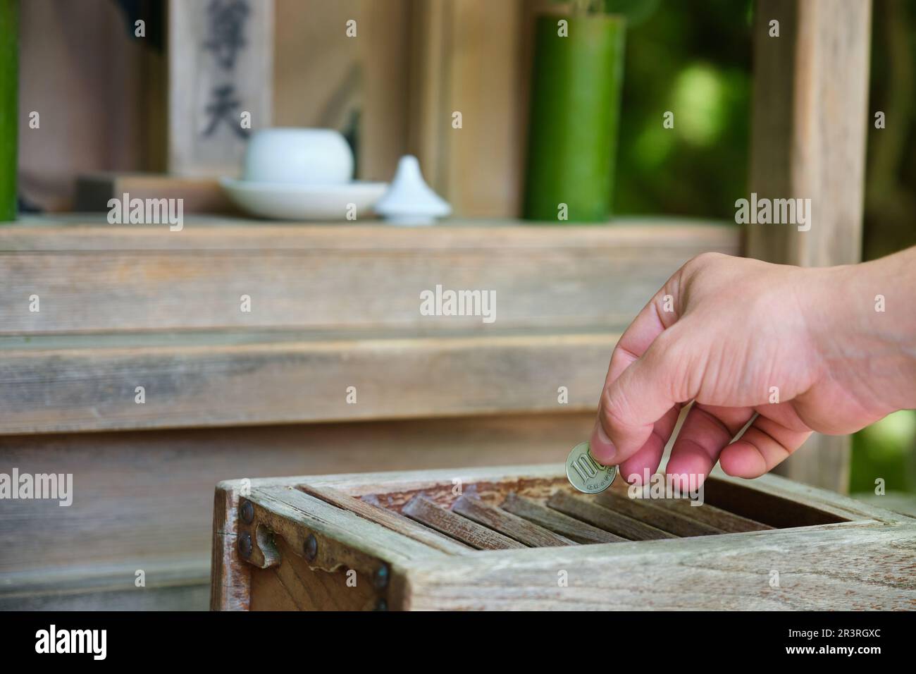 Hand making a offering in wooden offering box or Saisen Box, in