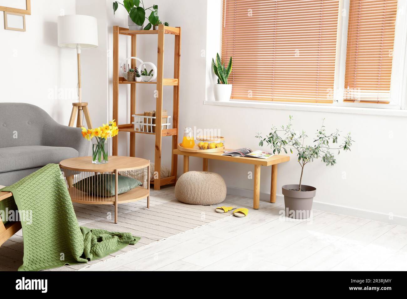 Interior of light living room with grey sofa and wooden coffee table ...