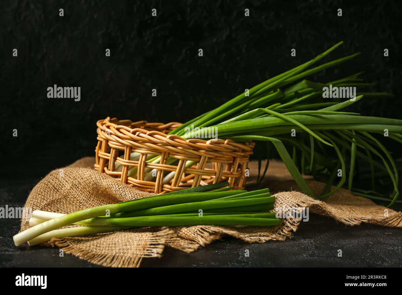 Wicker basket with fresh green onion on dark background Stock Photo - Alamy