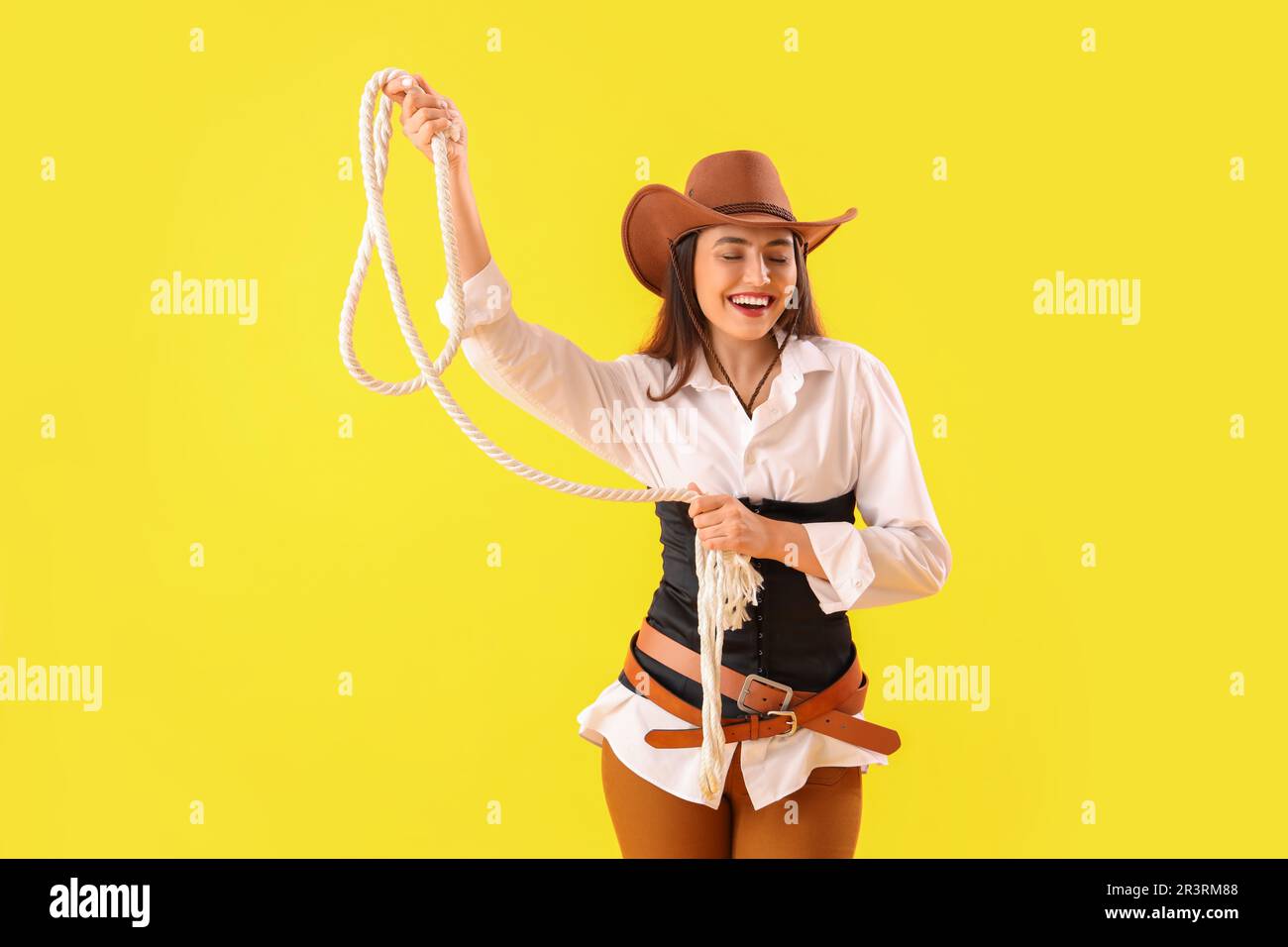 Beautiful cowgirl with lasso on yellow background Stock Photo - Alamy