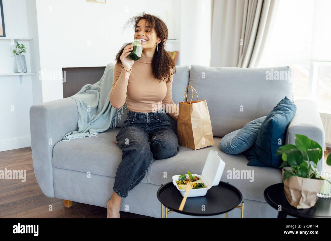 Satisfied afro american woman eating healthy balanced meal salad and green fresh or smoothie Stock Photo