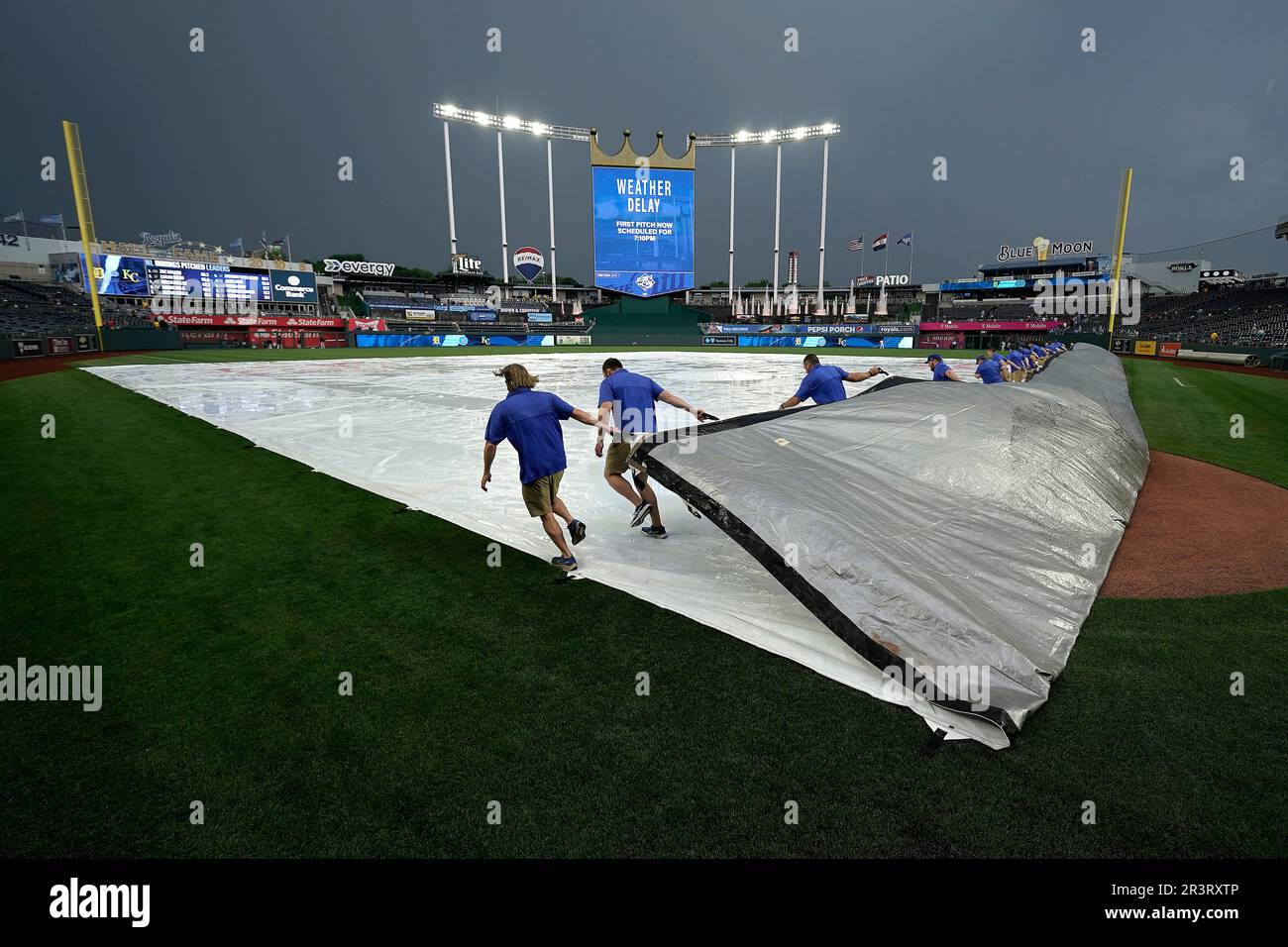 Members of the grounds crew pull the tarp after a rain delay before a