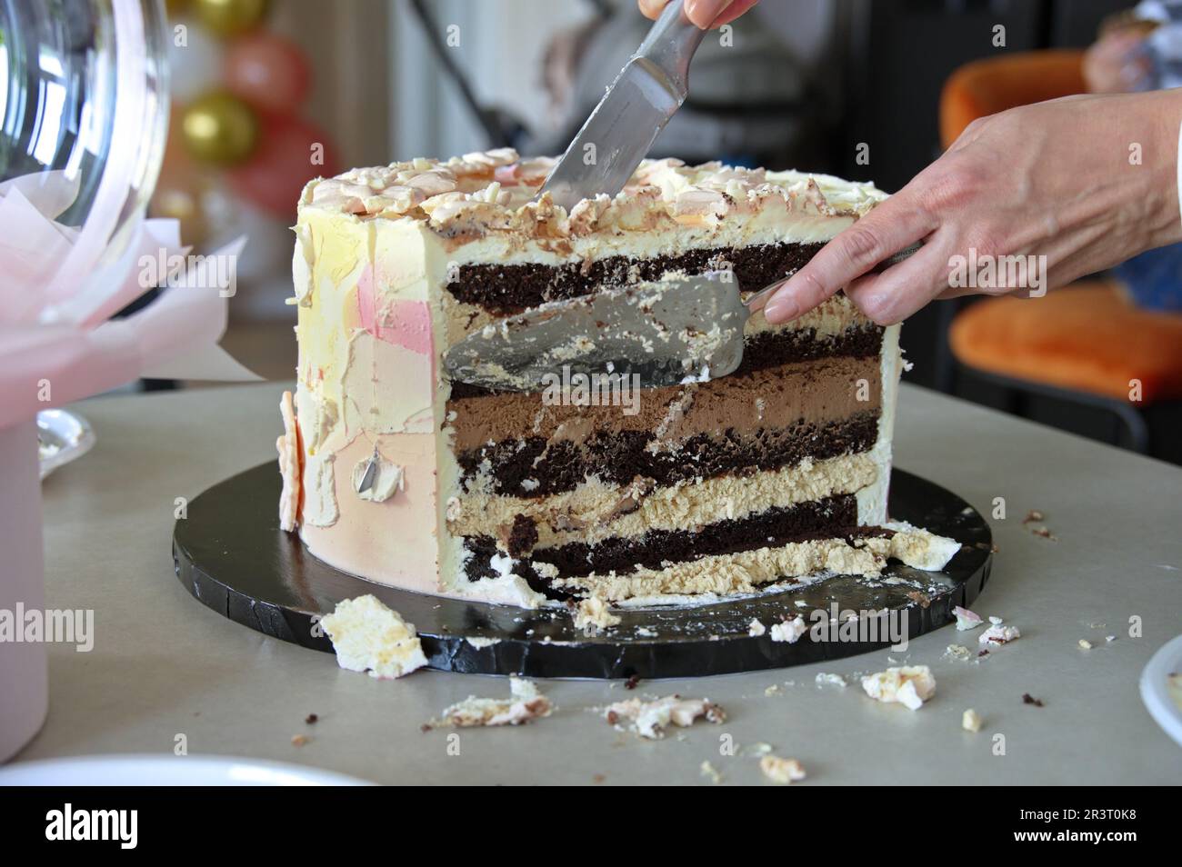 Cutting chocolate cake with many layers of cream Stock Photo