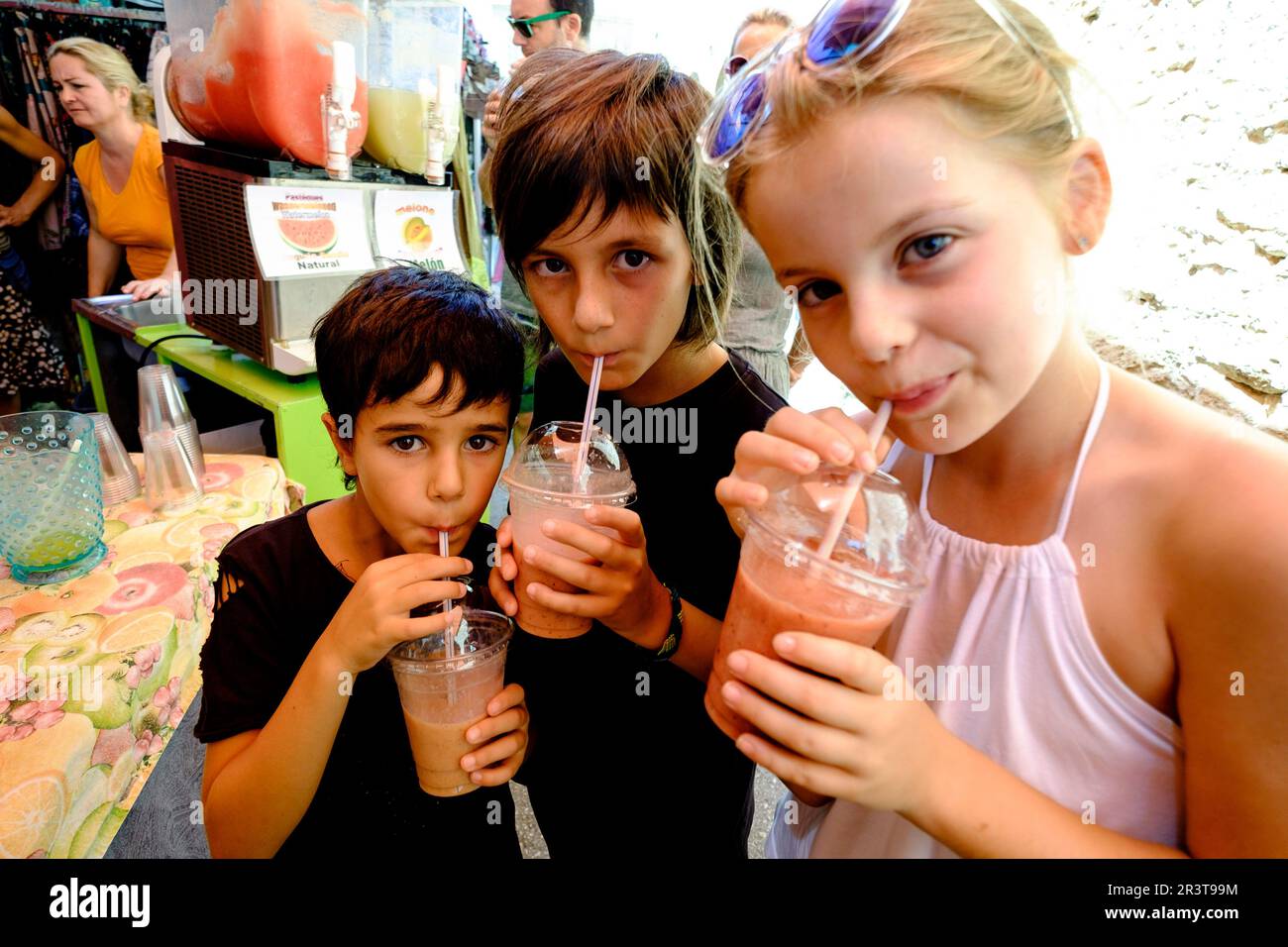 tres niños bebiendo batido de frutas, mercado comarcal, Santanyi, Mallorca, balearic islands, spain, europe. Stock Photo
