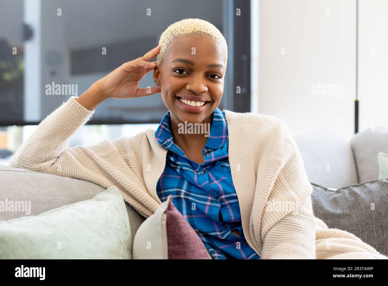 Portrait of happy african american woman sitting on sofa, looking at ...