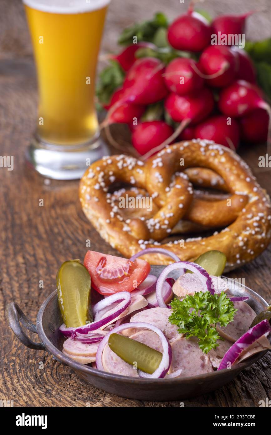 Bavarian sausage salad on dark wood Stock Photo