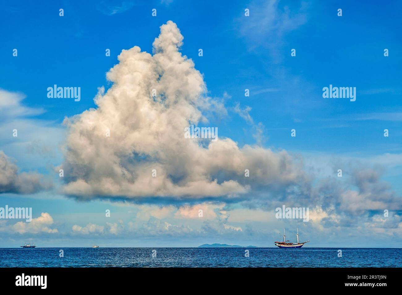 Large cloud (cumulus) and liveaboard dive boat, Kri Island, Dampier Strait, West Papua, West New Guinea, Indonesia Stock Photo