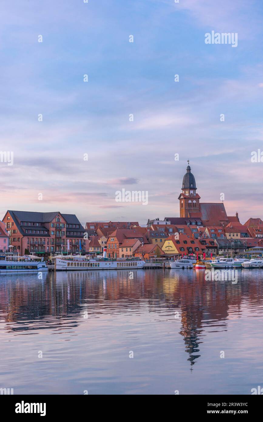 City harbour with motor boats, Waren, church St. Georgen, evening light, sky, water reflection, old town, renovation, portrait format, historical Stock Photo