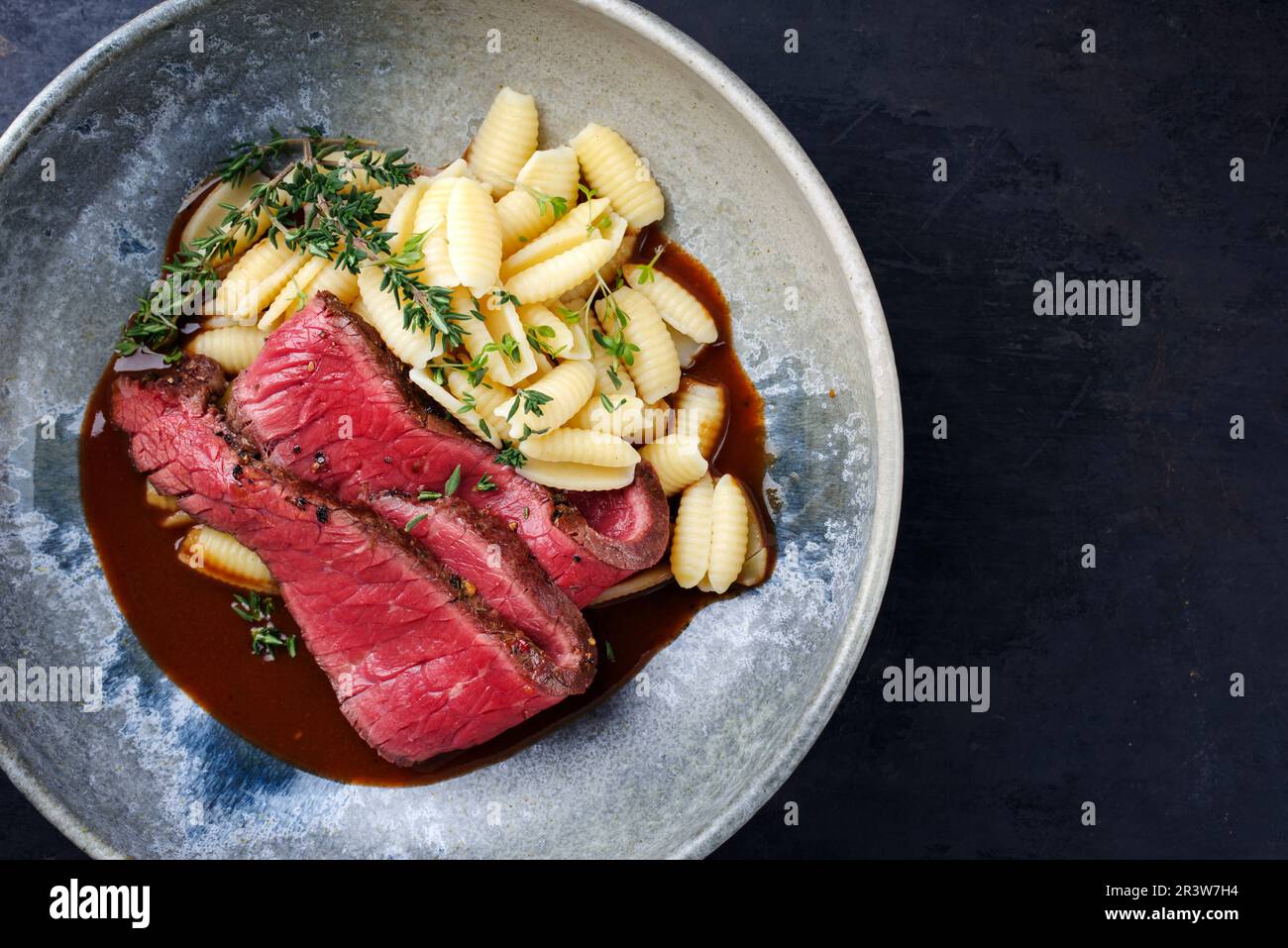 Traditional Italian chianina sliced roast beef with gnocchetti sardi pasta in spicy red wine sauce served as top view in a Nordi Stock Photo