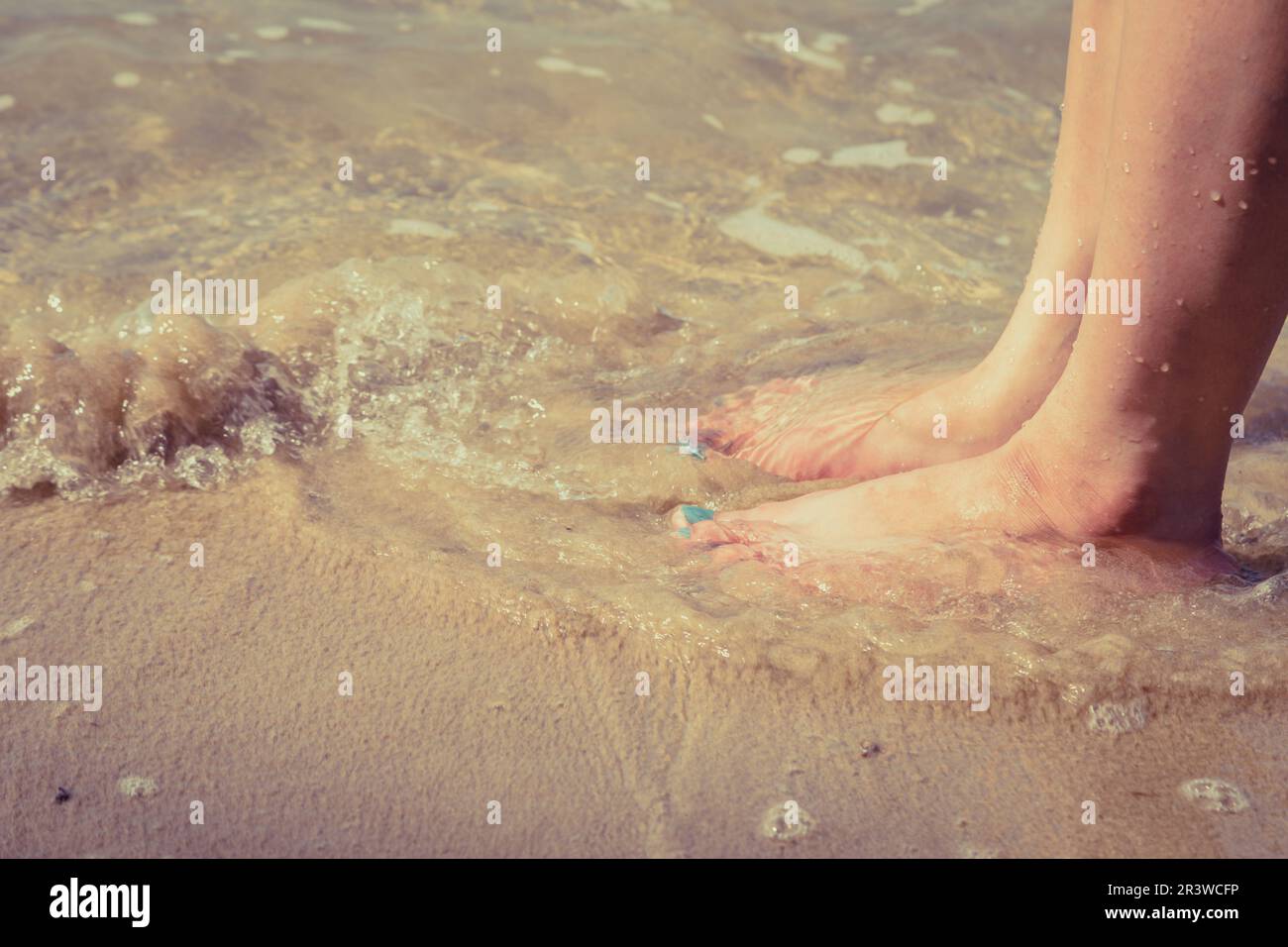 woman foot on the sand beach with sea water background Stock Photo