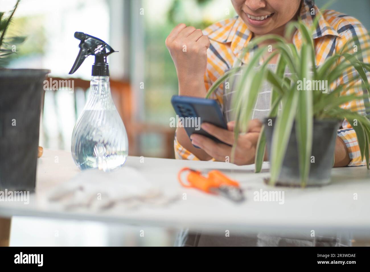 Successful female gardener using smartphone to sell plants at online