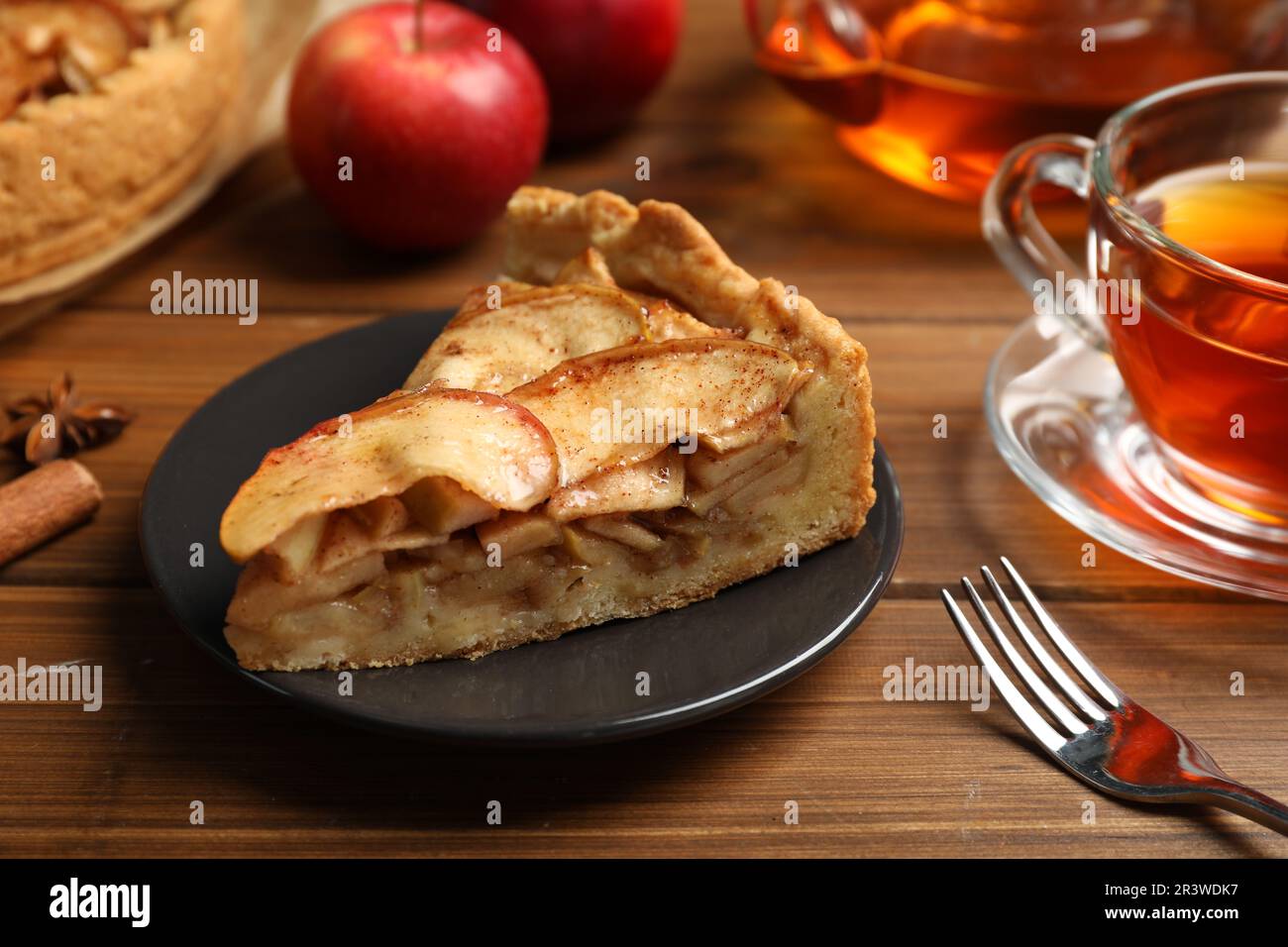Slice of delicious apple pie served with tea on wooden table, closeup Stock Photo