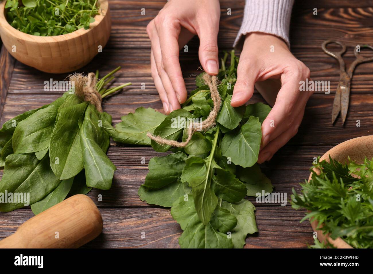 Woman with fresh green herbs at wooden table, closeup Stock Photo