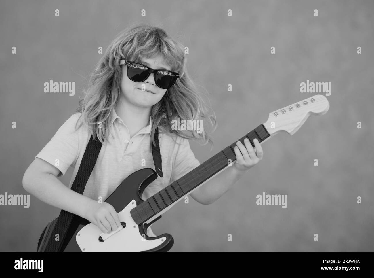 Child musician playing the guitar like a rockstar outdoor. Kid boy rock