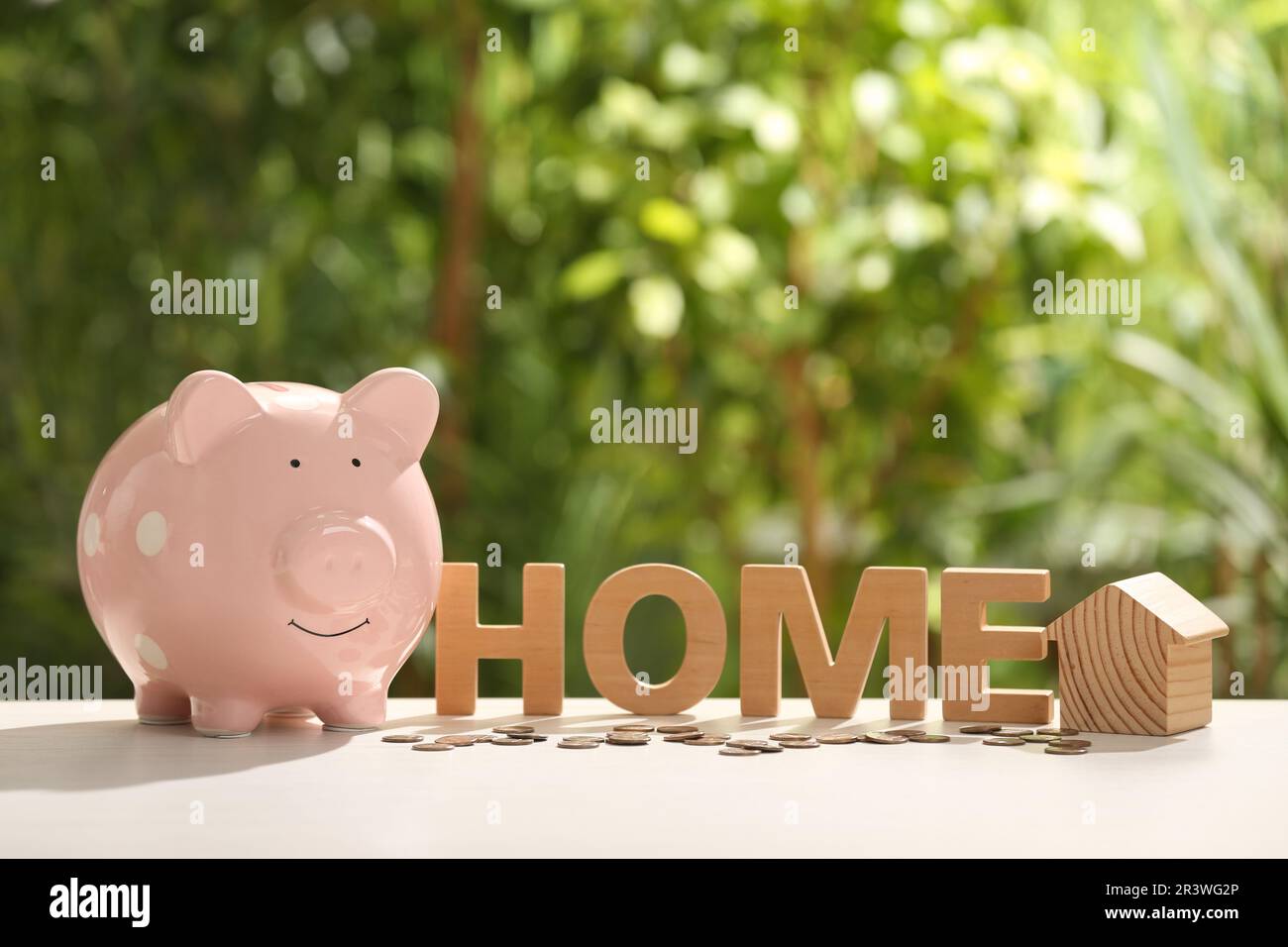 Piggy bank, word Home, house model and coins on table outdoors. Saving ...