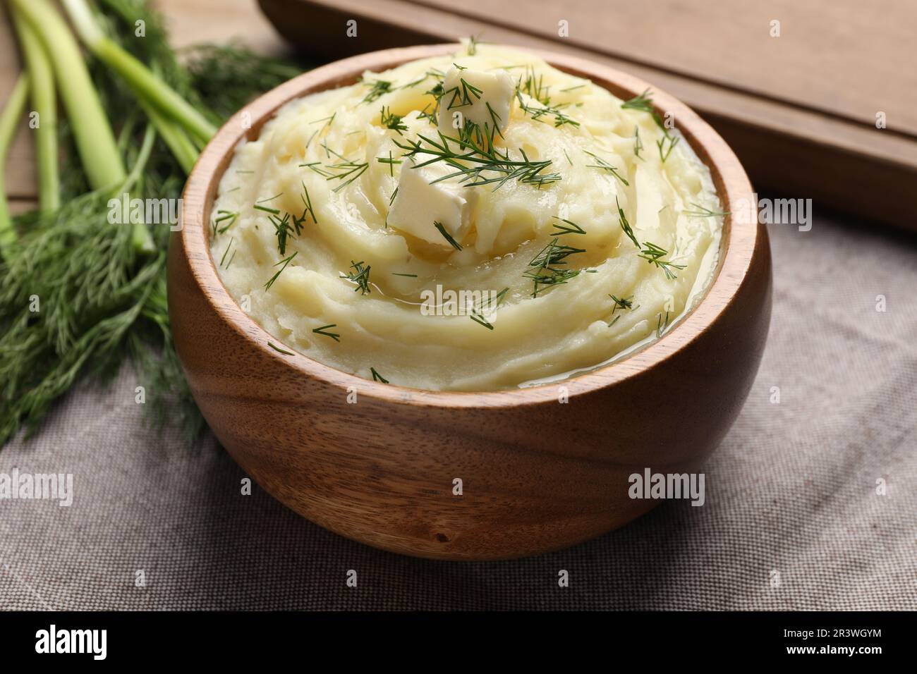 Bowl of delicious mashed potato with dill and butter on grey tablecloth, closeup Stock Photo