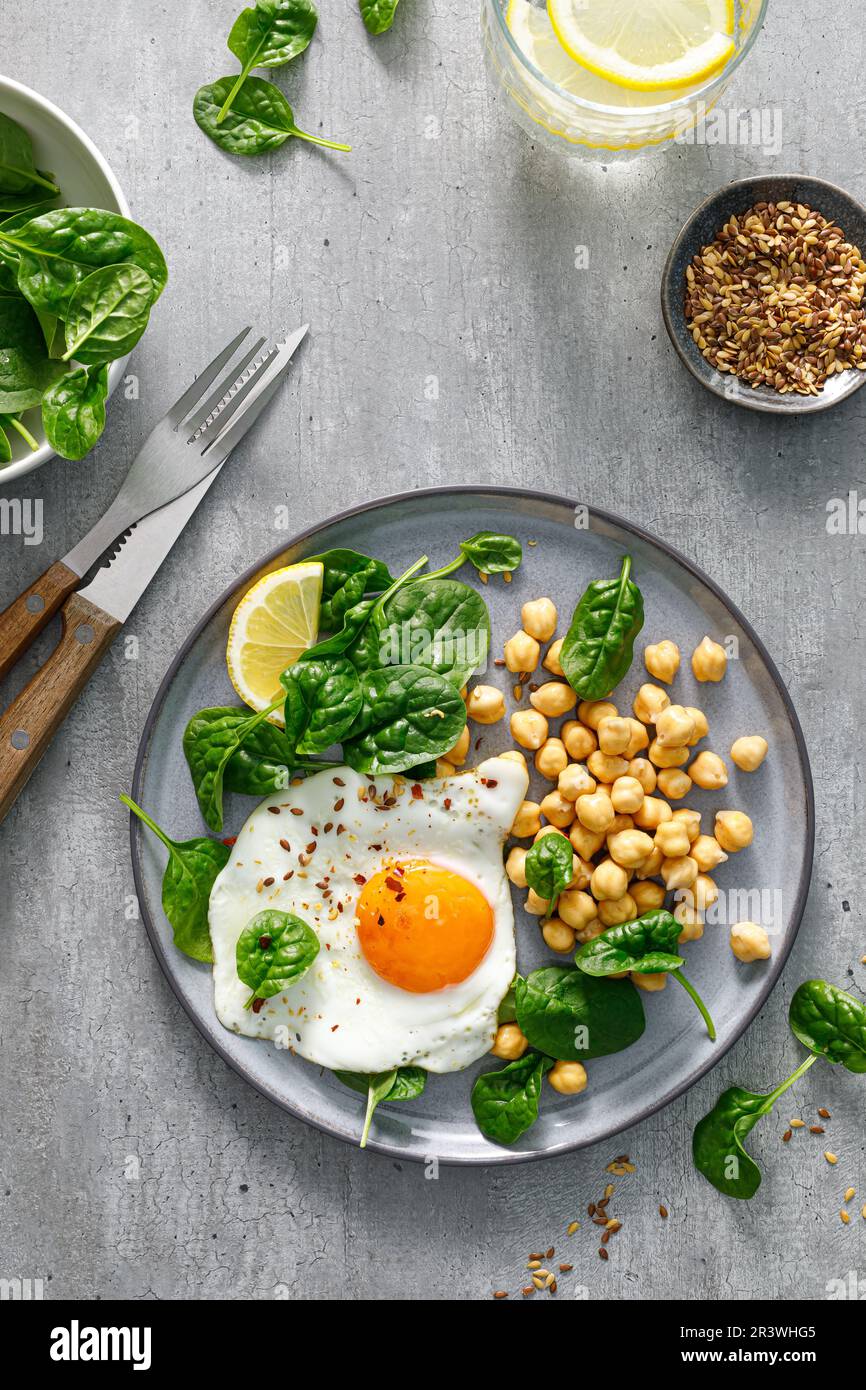 Egg fried, boiled chickpea and fresh spinach for healthy breakfast, top view Stock Photo