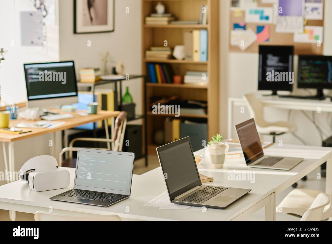 Horizontal image of modern IT office with computers on workplaces of programmers Stock Photo