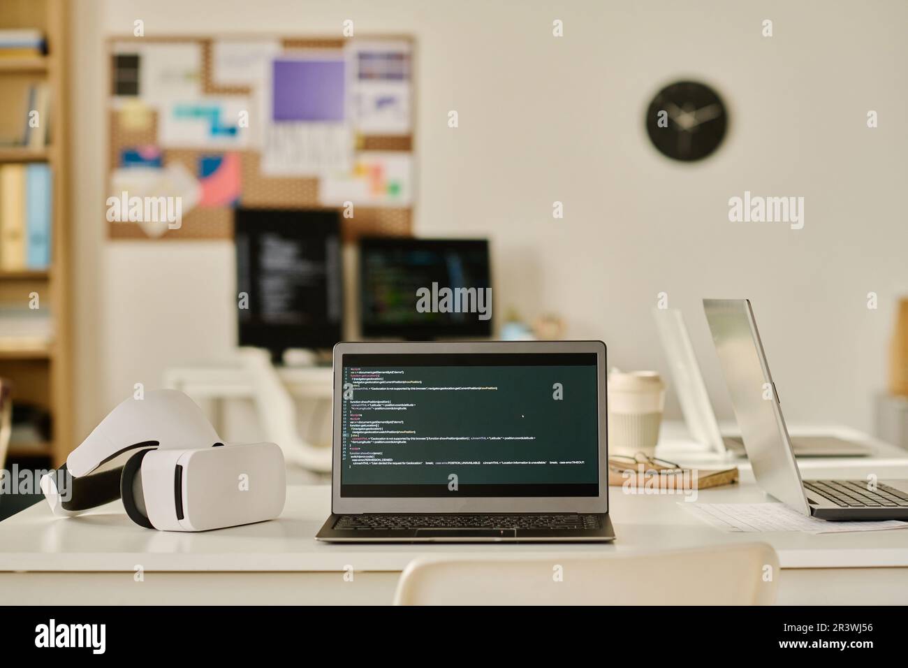 Laptop with program code on screen on table in IT office Stock Photo
