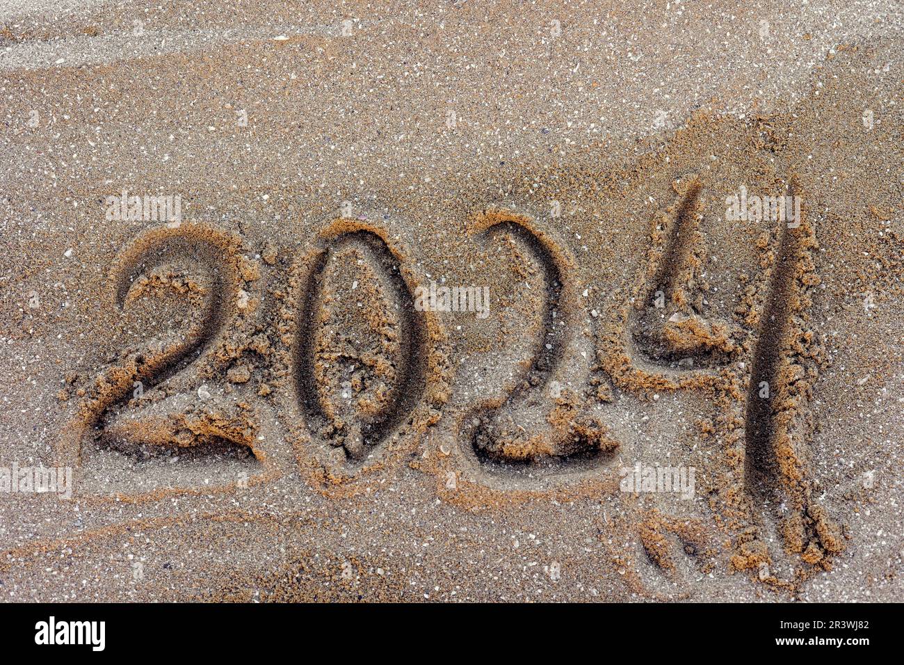 Happy New Year 2024, lettering message handwritten on the beach Numbers