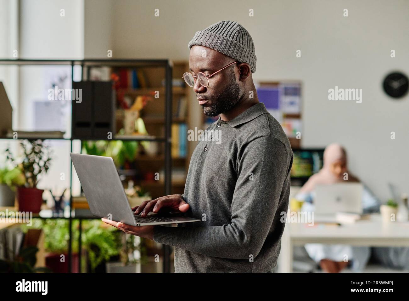 African American developer typing on laptop while standing in IT office Stock Photo