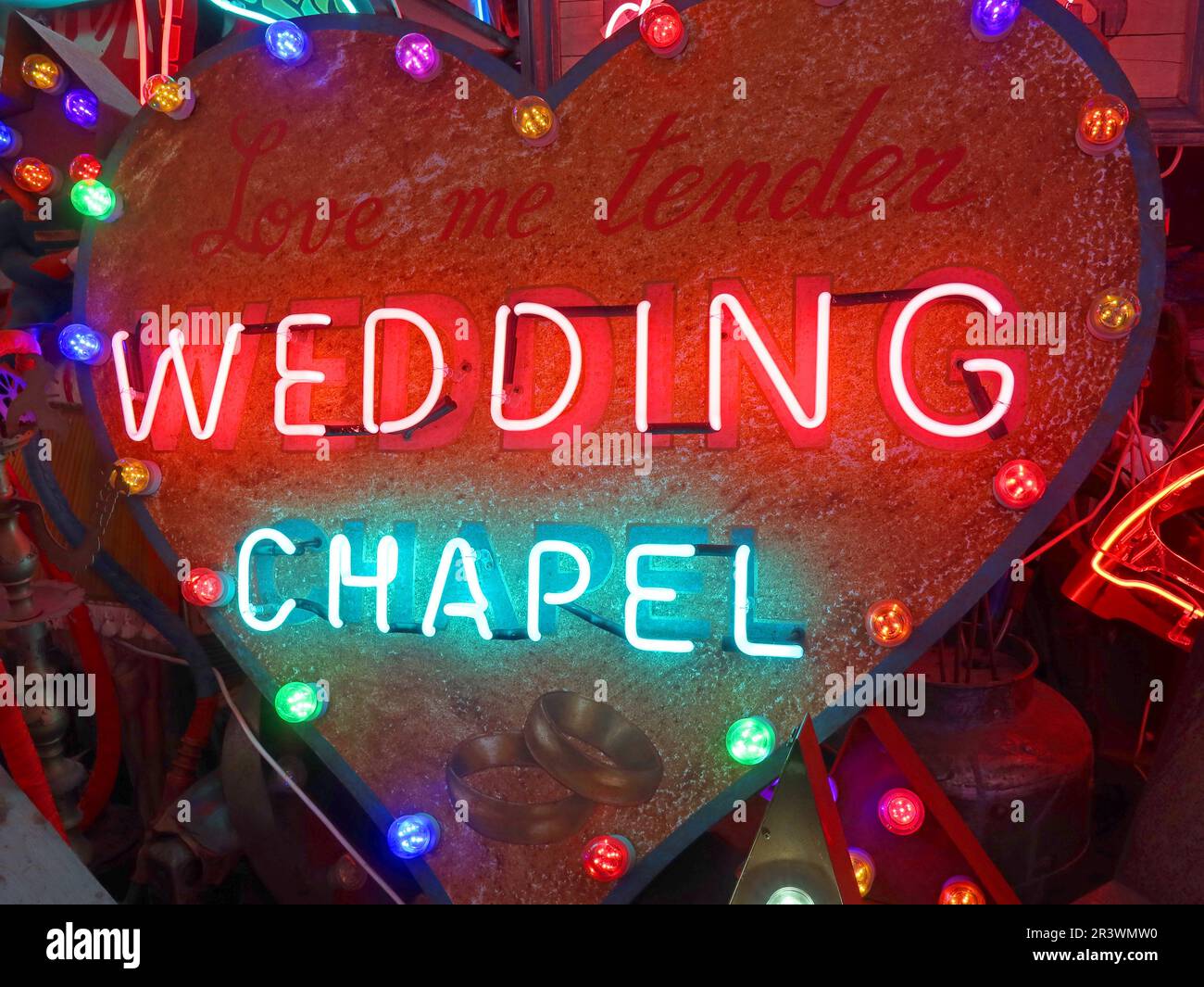 Heart-shaped neon sign reading “Wedding Chapel” displayed among colourful illuminated artwork at God’s Own Junkyard in Walthamstow, East London Stock Photo