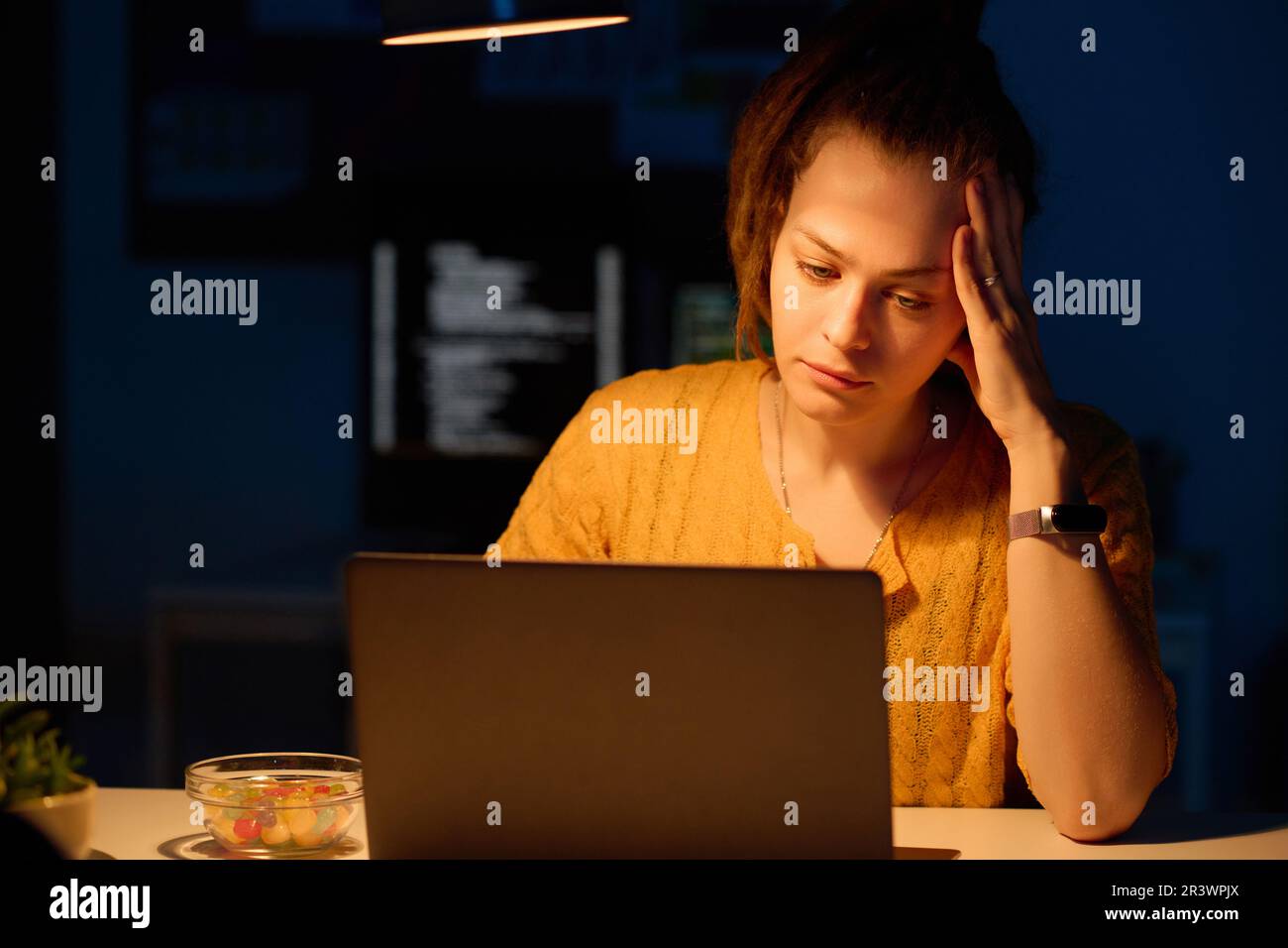 Young tired programmer working on computer in office till late night Stock Photo