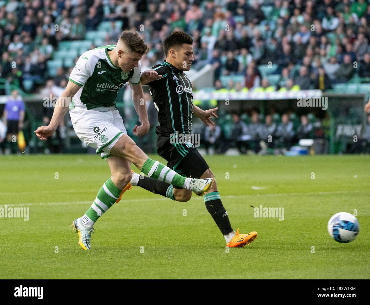 EDINBURGH, UK. 24th May, 2023. HibsÕ striker, Kevin Nisbet, manages to get his shot away despite the attention of Celtic forward, Liel Abada, during the match between Hibernian and Celtic in the cinch Premiership at Easter Road Stadium, Edinburgh, Midlothian, UK. 24/5/2023. Credit: Ian Jacobs/Alamy Live News Stock Photo