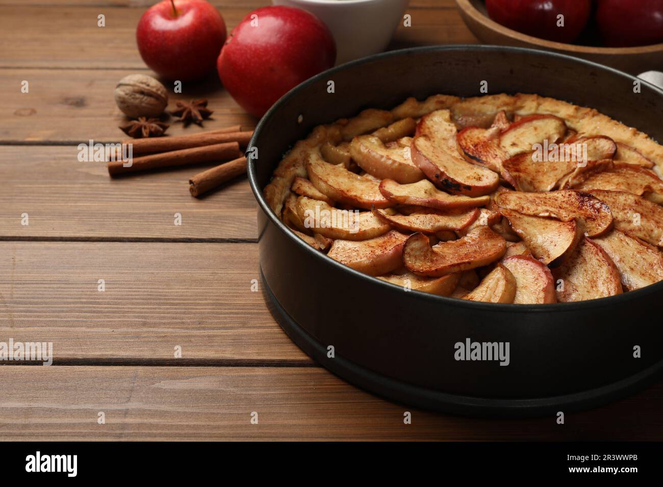 Delicious apple pie and ingredients on wooden table. Space for text Stock Photo