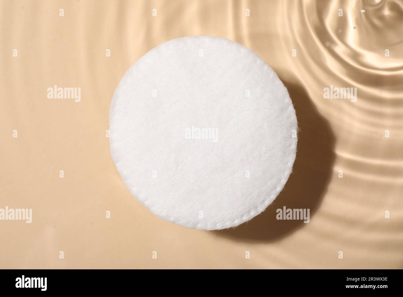 Cotton pad and micellar water on beige background, top view Stock Photo