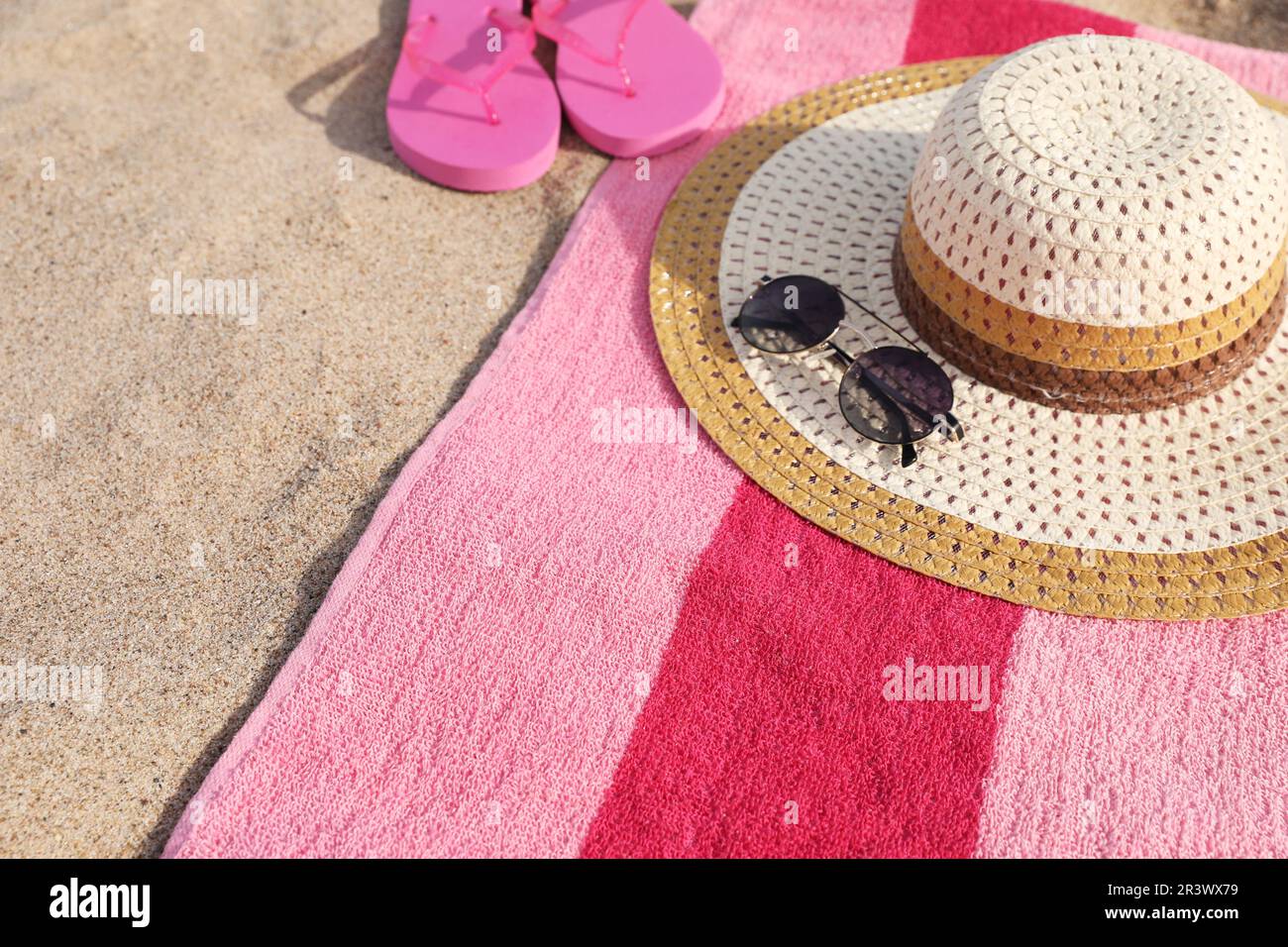 Beach towel with slippers, straw hat and sunglasses on sand Stock Photo ...