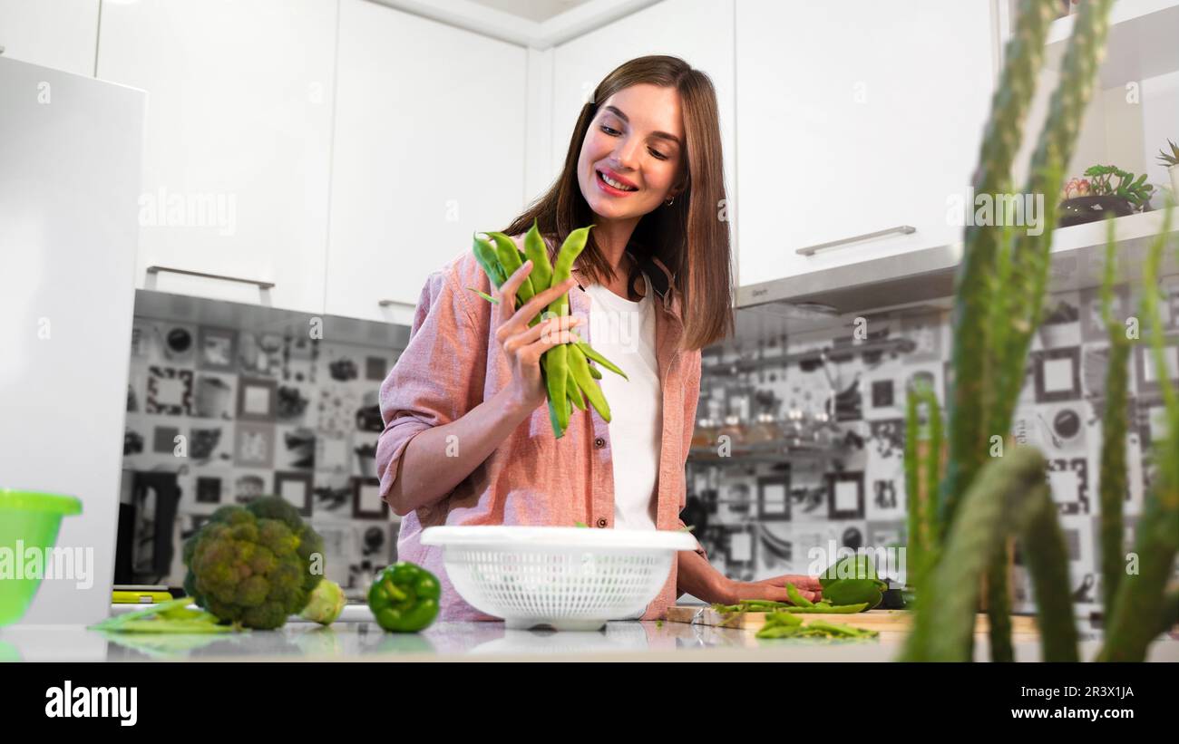 A Young smiling beautiful woman holding romano helda green beans in hands. The concept of a healthy nutrition and vegetarian diet food. Lifestyle and Stock Photo