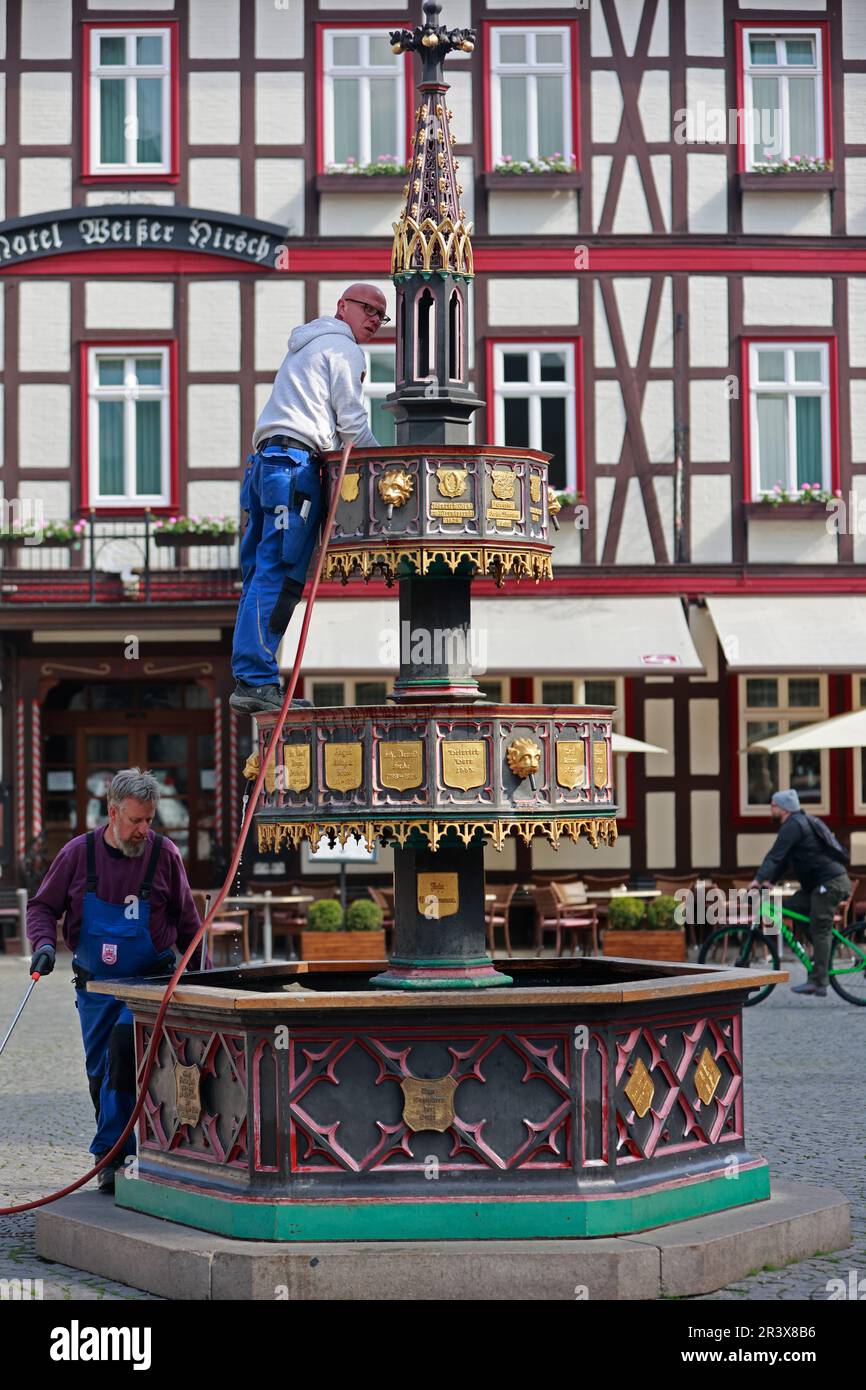 25 May 2023, Saxony-Anhalt, Wernigerode: Employees of the building yard of the city of Wernigerode clean the historic market fountain. The 'Wohltäterbrunnen', so called because of the names on it of people who have rendered outstanding services to the city is a popular photo motif. Germany can look forward to plenty of sunshine and summer temperatures on this long Whitsun weekend. Only in the north, according to the forecast of the German Weather Service (DWD), a few clouds will push in front of the sun. At the edge of the Alps, short showers and thunderstorms can not be completely ruled out, Stock Photo