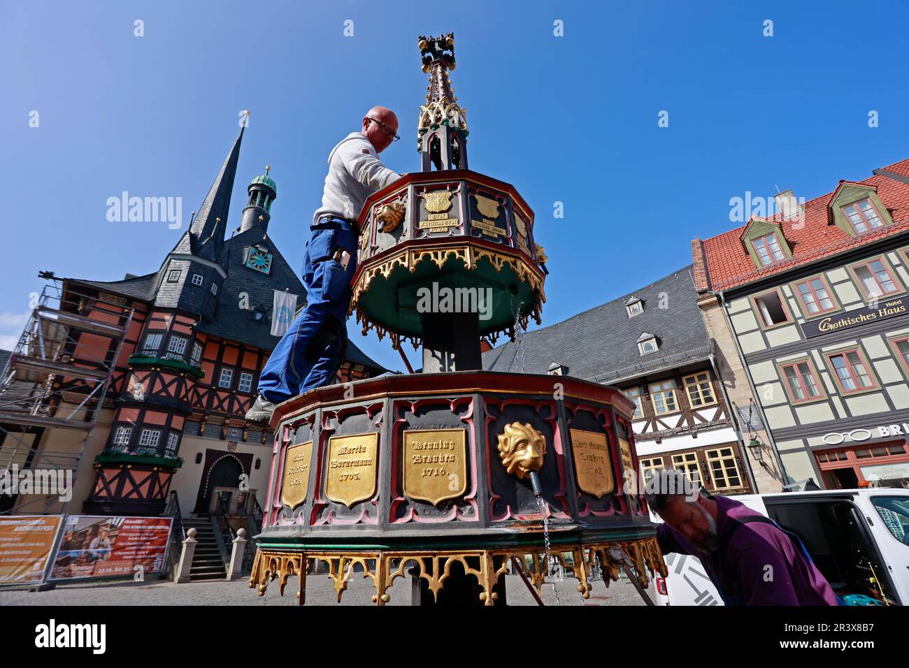 25 May 2023, Saxony-Anhalt, Wernigerode: Employees of the building yard of the city of Wernigerode clean the historic market fountain. The 'Wohltäterbrunnen', so called because of the names on it of people who have rendered outstanding services to the city is a popular photo motif. Germany can look forward to plenty of sunshine and summer temperatures on this long Whitsun weekend. Only in the north, according to the forecast of the German Weather Service (DWD), a few clouds will push in front of the sun. At the edge of the Alps, short showers and thunderstorms can not be completely ruled out, Stock Photo