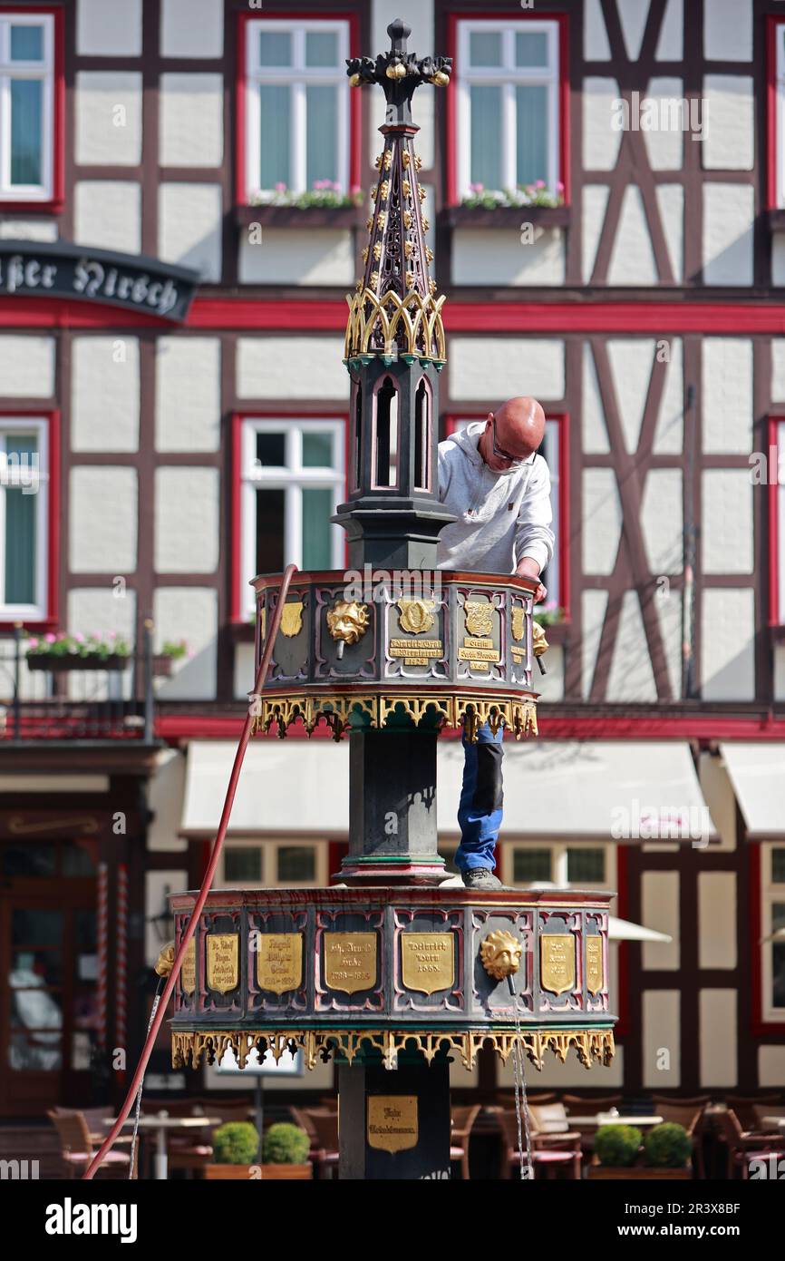 25 May 2023, Saxony-Anhalt, Wernigerode: Employees of the building yard of the city of Wernigerode clean the historic market fountain. The 'Wohltäterbrunnen', so called because of the names on it of people who have rendered outstanding services to the city is a popular photo motif. Germany can look forward to plenty of sunshine and summer temperatures on this long Whitsun weekend. Only in the north, according to the forecast of the German Weather Service (DWD), a few clouds will push in front of the sun. At the edge of the Alps, short showers and thunderstorms can not be completely ruled out, Stock Photo