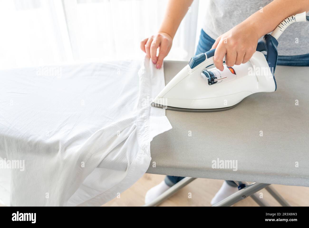 Female hands ironing white shirt collar on ironing board Stock Photo