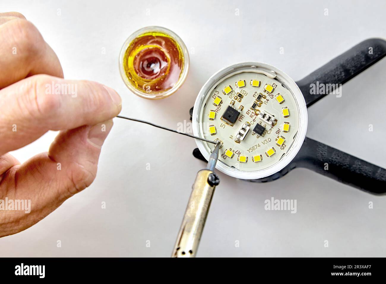 Soldering a burnedout LED into an LED light bulb. Hand with a
