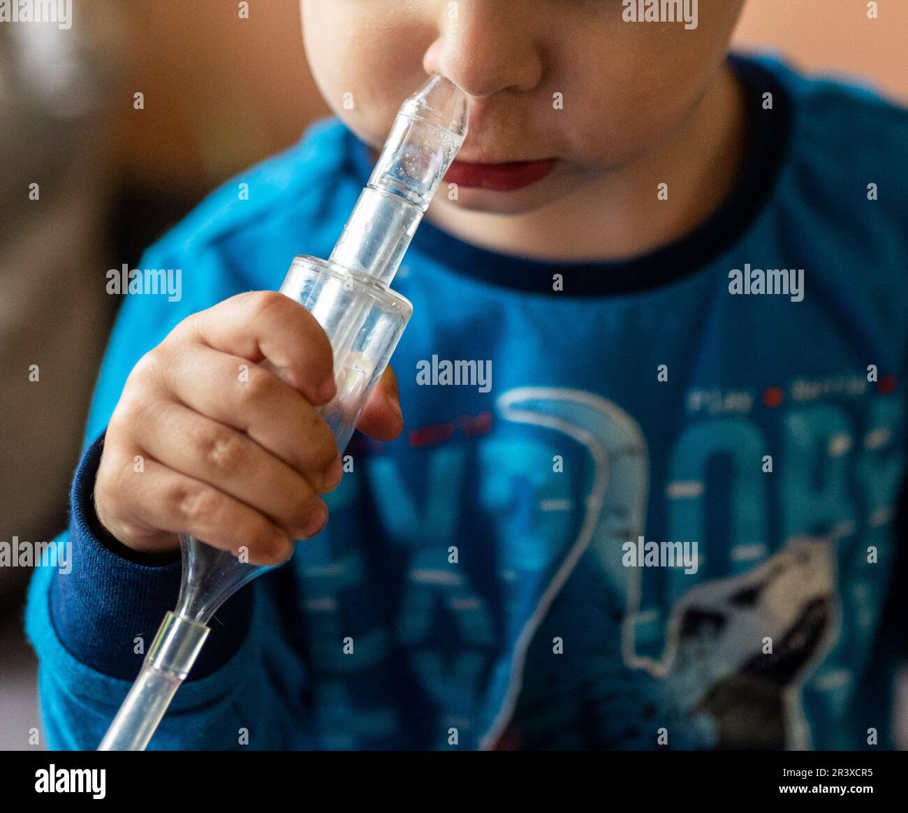 child with cold cleaning his running nose on his own with a vacuum operated nasal aspirator Stock Photo