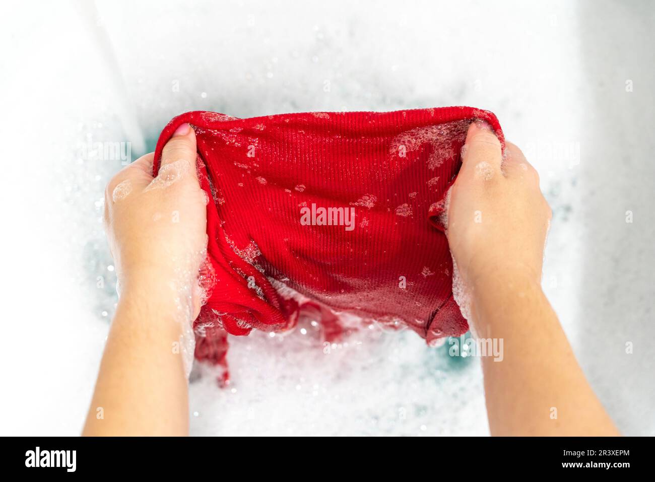 Removing stain with handwash from red clothes Stock Photo
