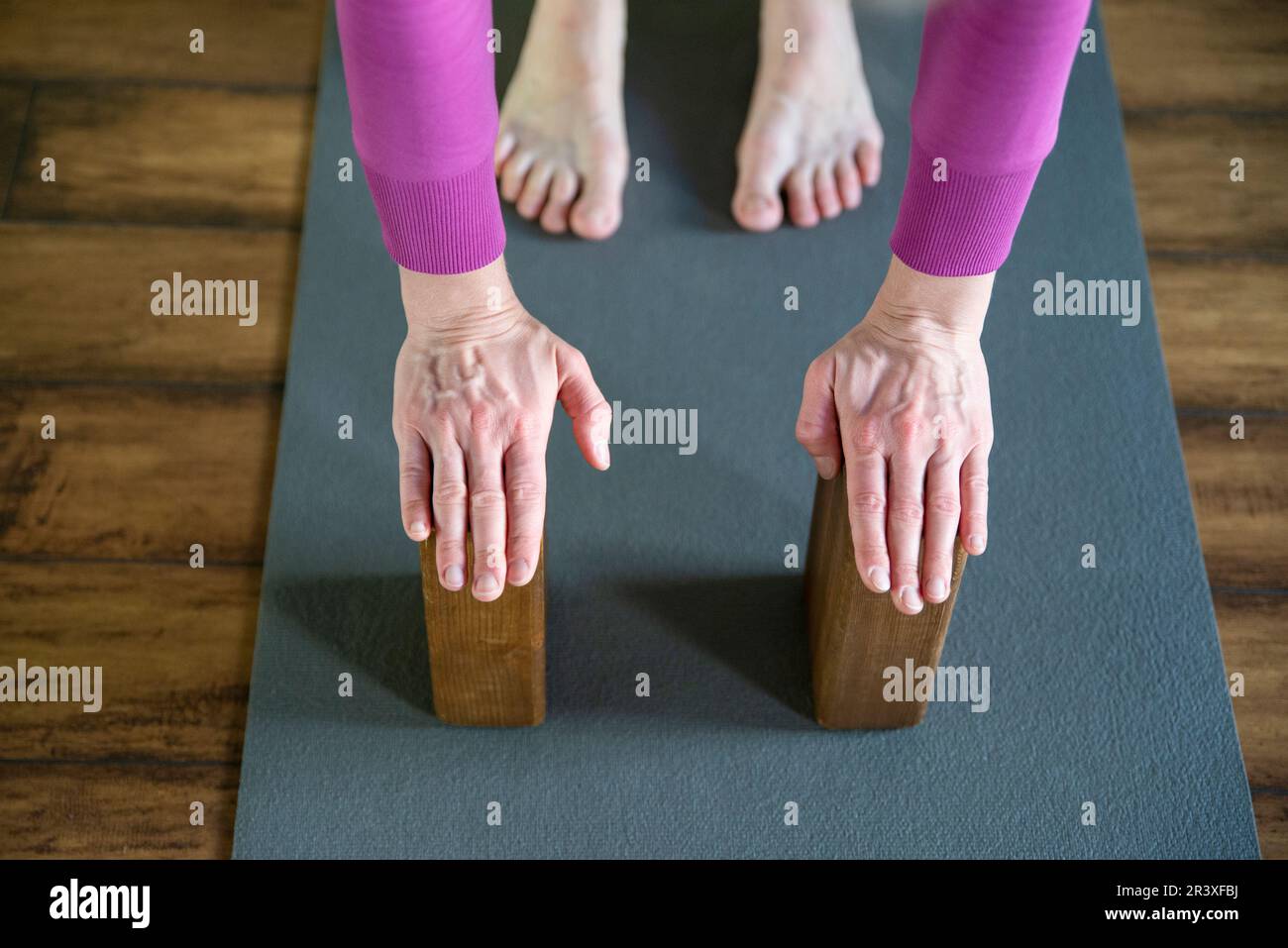Women practicing yoga stretching using wooden blocks with hands ...