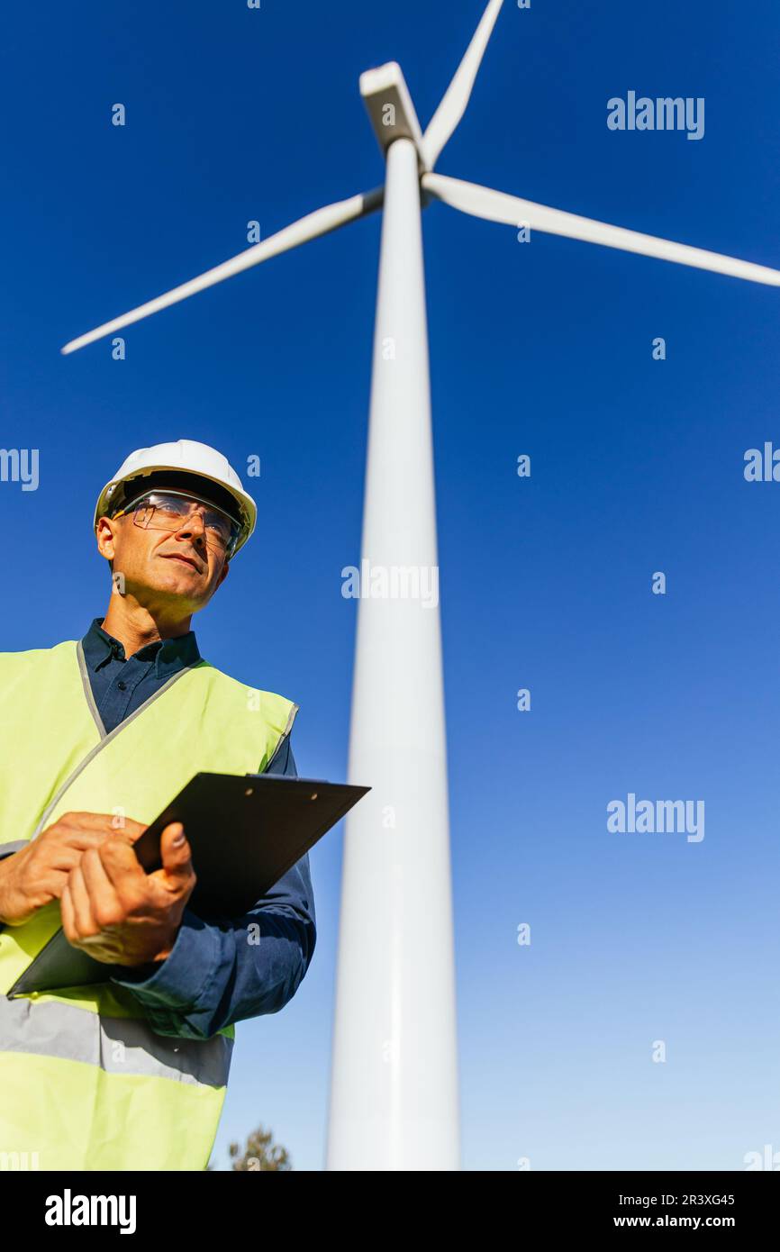Professional male engineer checking the wind turbine while working in a