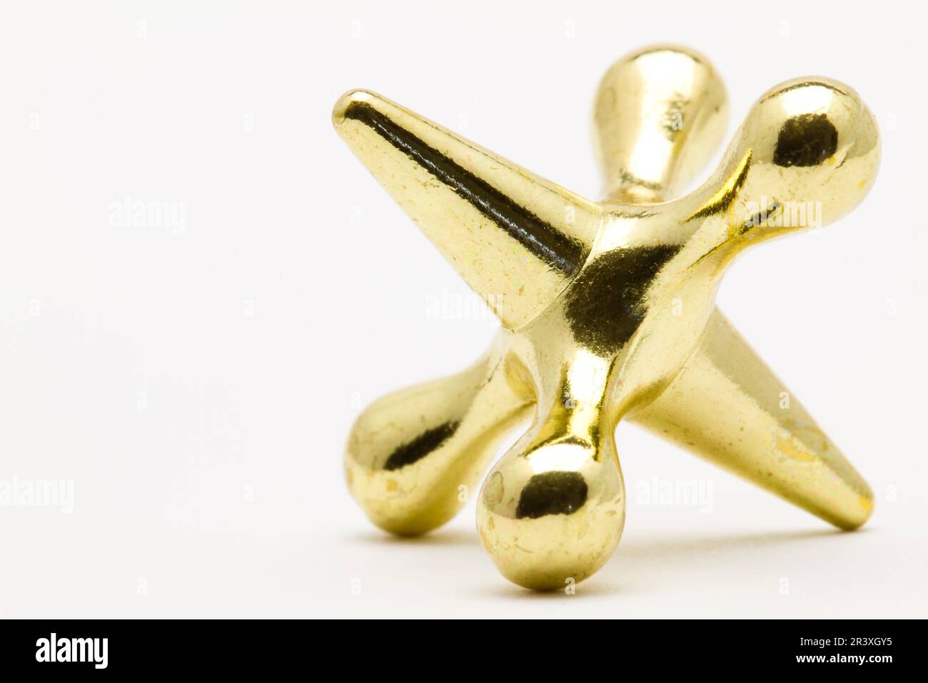 A gold colored jacks game piece Stock Photo Alamy