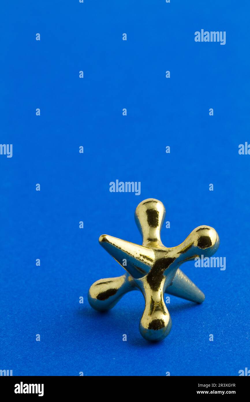 A gold colored jacks game piece Stock Photo Alamy