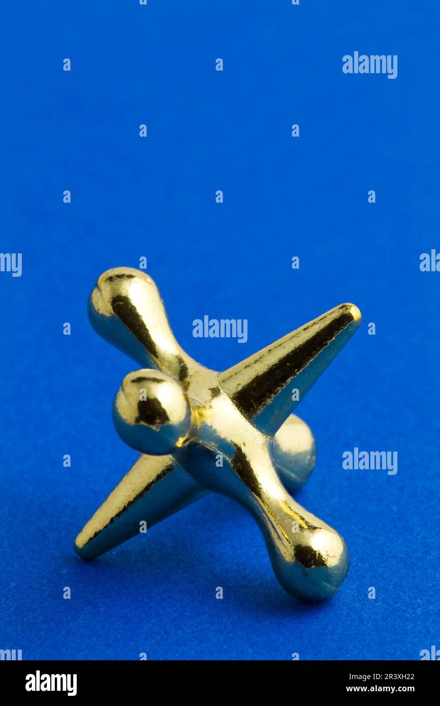 A gold colored jacks game piece Stock Photo Alamy