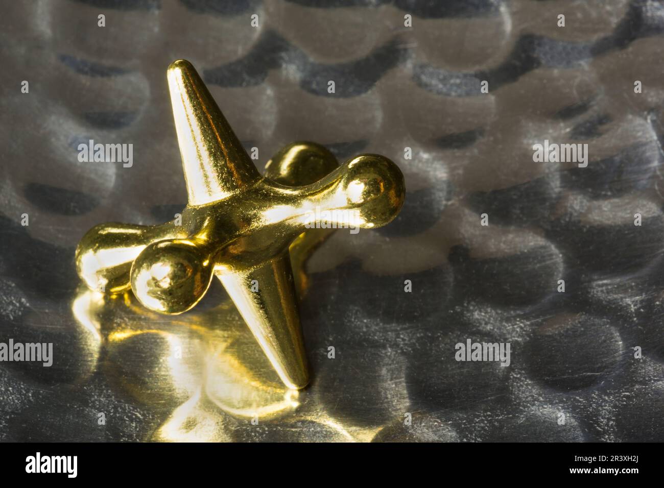 A jacks game piece on a dimpled metal background Stock Photo Alamy