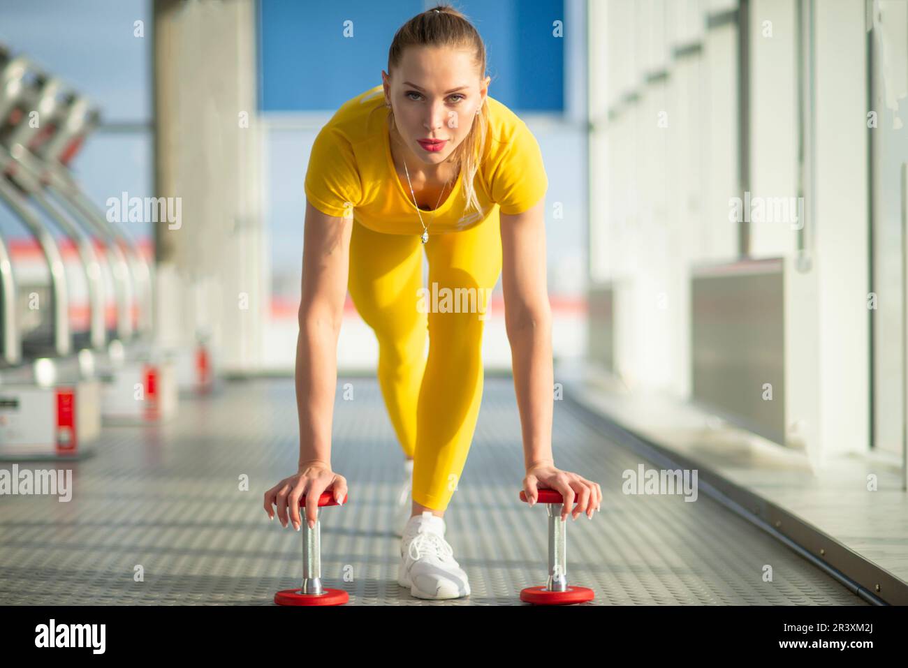 Physically fit woman at the gym with dumbbells ready to strengthen her arms and biceps Stock Photo