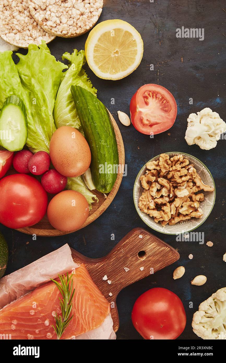 Ketogenic, Paleo, FODMAP, diet concept. Fruits,vegetables, salmon, greens on black table background. Stock Photo