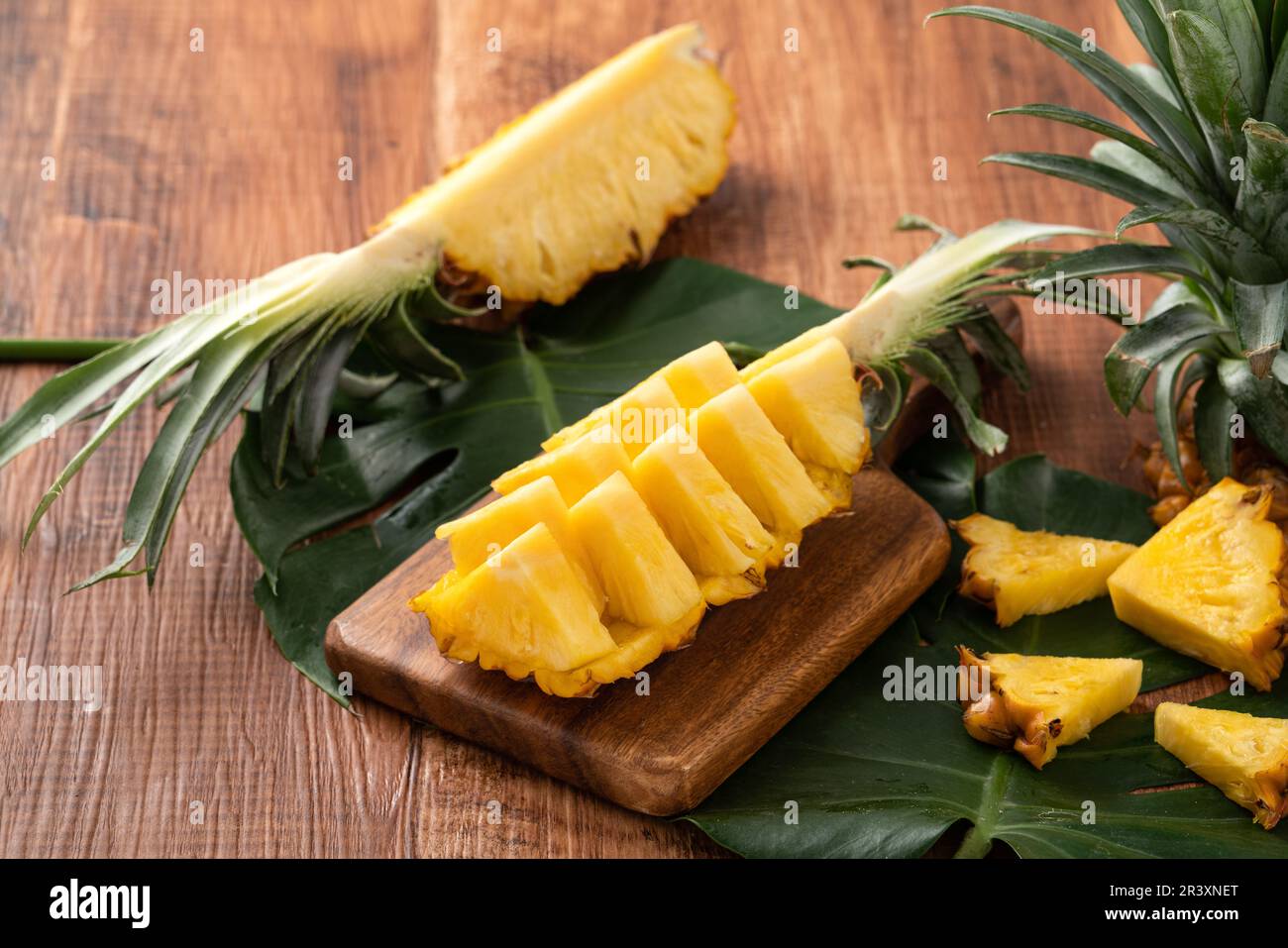 Close up of fresh cut pineapple on a tray over dark wooden table background. Stock Photo