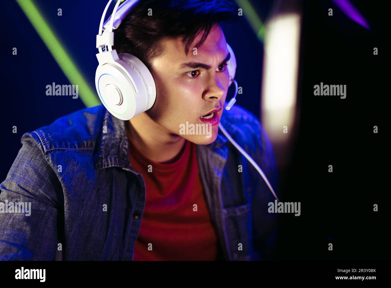 Gamer staring at the computer screen with an expression of shock and disbelief, trying to get a closer look at what he’s seeing in this intense moment Stock Photo